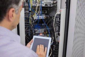 Man doing server maintenance with tablet pc in data center