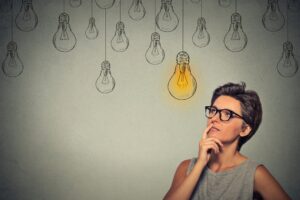 Portrait thinking woman in glasses looking up with light idea bulb above head Portrait thinking woman in glasses looking up with light idea bulb above head