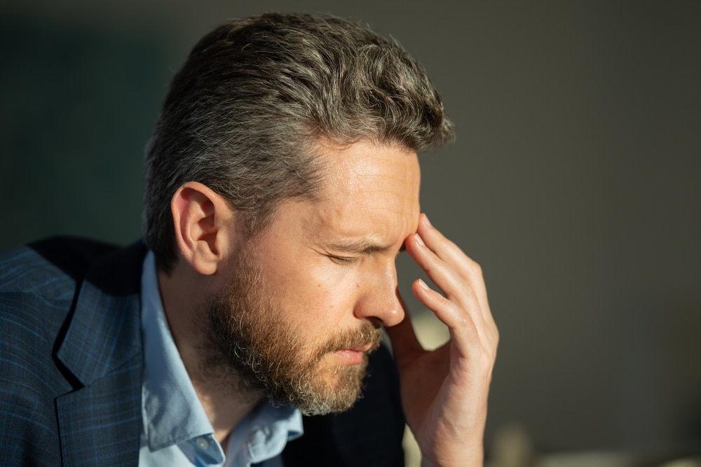Tired exhausted man suffering from headache. Overworked burnout man feeling migraine head strain. Bored business man has office syndrome. Office worker, manager or freelancer having a headache. Common Triggers of Reactance in Sales